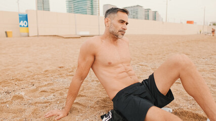 Middle aged muscular man sitting relaxed on the beach