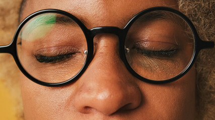 Close-up of girl in glasses with closed eyes isolated on orange background