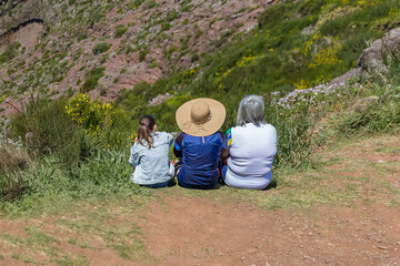 View of women sitting back to back on mountain slope, 3 different generations, casual wear, in Pico...