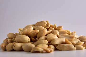 Small handful of nutritious salted peanuts close-up on a white background is lined in a heap. Salty delicious peeled peanuts close-up, an appetizer with beer