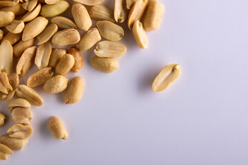 On a white background, several pieces of peanuts, top view. Delicious ripe salted peanuts in the upper left corner on a white background
