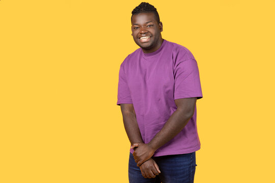 Shy African man looking at camera with toothy smile, studio