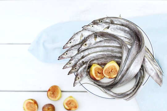 Silver eel,hairtail fish, ribbonfish, lepidopus caudatus, komira, saber fish, belt fish ikan layur, cutlassfish, tachiuo, long fish, seafood,on a white wooden table, top view, free space, background