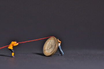 workers prevent the fall of the one euro coin with rope and hold on. miniature figures scene