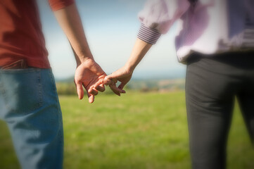 A couple is holding hands in the autumn or spring day in the park. Close-up of loving couple holding hands while walking. Selective focus