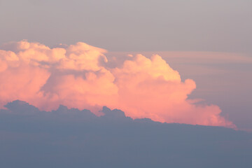 Layers of cumulonimbus clouds pile up on the horizon, the top ones catching the warm light of the setting sun while the lower levels are in shadow.