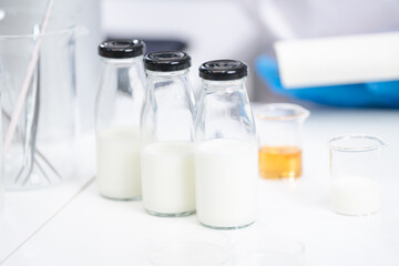 Food scientist testing new stuff samples of dairy products in the laboratory, female laboratory assistant checks a quality of milk, bottles glassware and glasses of milk to testing lactose forms