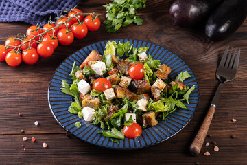 Salad with fried eggplant, herbs.tomatoes and feta cheese on a wooden background
