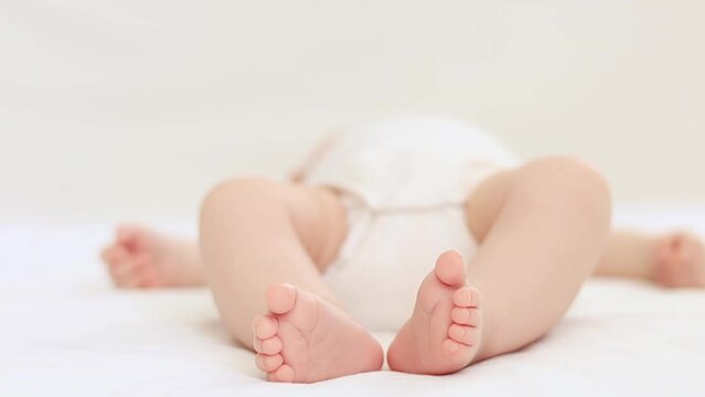 the legs of a newborn baby on the bed in a white isolated photo, the heels of the baby close-up in focus