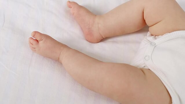 the legs of a newborn baby on the bed in a white isolated photo, the heels of the baby close-up in focus