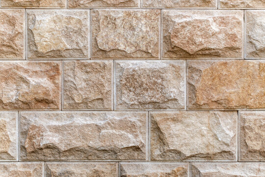 Wall lined with decorative chipped rectangular tiles, close-up, uniform texture background .