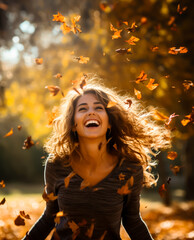 Joyful smiling Woman throwing leaves into the air in a park in the autumn. Colors are warm orange...
