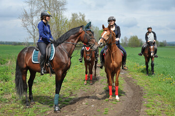 Riders ride their horses side by side on a dirt road back to the horse farm