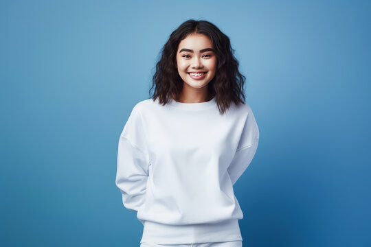 Young woman wearing white sweatshirt mockup isolated on blue background. Generative AI.
