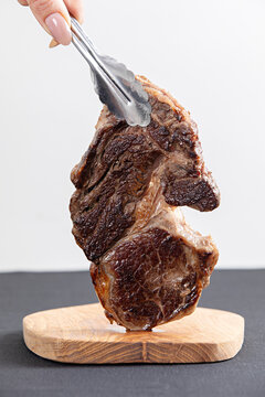Steak held by kitchen tongs