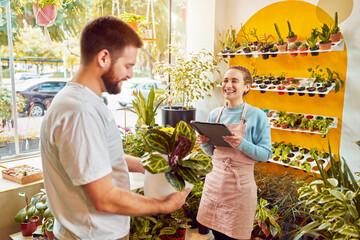 beautiful caucasian female employee owner serving customer smiling in small plant business
