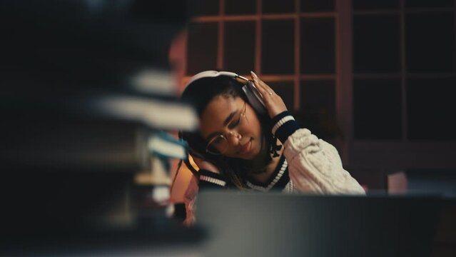 Young woman listening to music in headphones, procrastinating at dull work