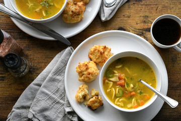 Chicken noodle soup and cheese biscuits on dinner table