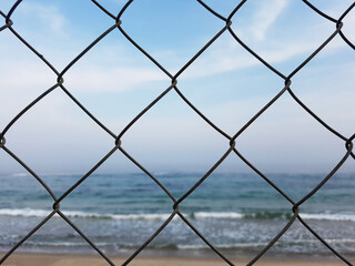 Protective mesh on beach background. Sea behind bars. Beach is closed. Swimming is prohibited concept