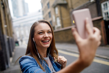 Young woman using a smart phone while walking down a sidewalk in London