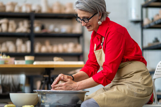 Woman potter molding pot shape on pottery wheel at her workshop. - Powered by Adobe