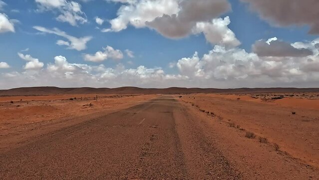 Car POV driving on Tunisia desert road with clouds in blue sky