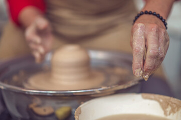 Fototapeta na wymiar Ceramic bowl on a potter's wheel, ceramist's hands.