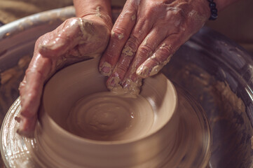 Fototapeta premium Ceramic plate on a potter's wheel, ceramist's hands.