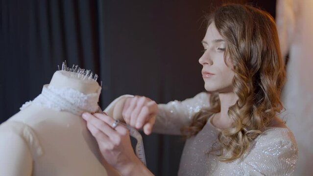 talented fashion designer gay man is modeling wedding dress in fashion atelier, non-binary queer man