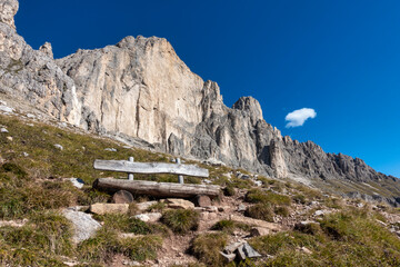 Wooden bench against deep blue sky in front of dolomites steep face, Rosengarten, South Tyrol