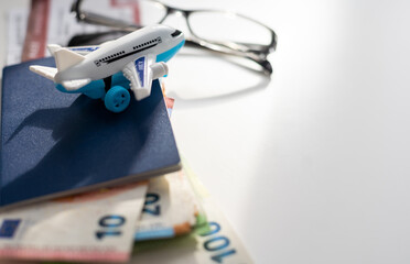 Airplane toy with passports and money on black background. Air trip and vacation.