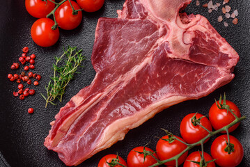 Raw fresh juicy beef t-bone steak with salt, spices and herbs