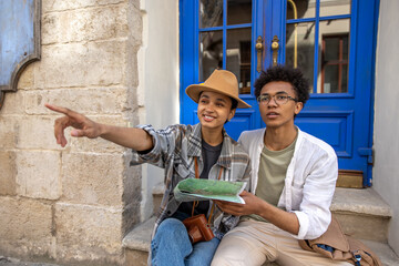 Young couple sitting on the door step and discussing the route