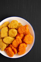 Homemade Spicy Chicken Nuggets Mix on black background, top view. Flat lay, overhead, from above. Copy space.