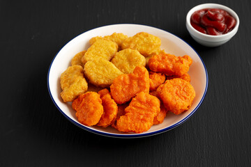 Homemade Spicy Chicken Nuggets Mix on black background, side view.