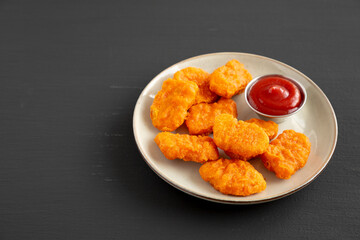 Homemade Spicy Chicken Nuggets on a Plate on a black background, side view.