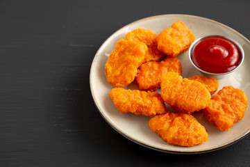 Homemade Spicy Chicken Nuggets on a Plate on a black background, side view. Copy space.