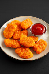 Homemade Spicy Chicken Nuggets on a Plate on a black background, side view.