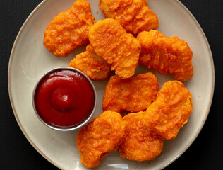 Homemade Spicy Chicken Nuggets on a Plate on a black background, top view. Close-up.