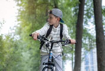 A happy boy of 10 years old is having fun in the forest on a bicycle on a beautiful summer day. Active child on a bike. Safety, sports, recreation with kids concept