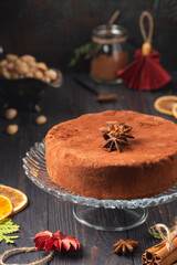Round Italian traditional Christmas sweet Panforte with cocoa, pistachios and candied fruits on a dark wooden background.