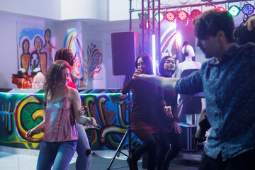 Man and woman dancing and partying at disco gathering in nightclub. Young caucasian couple improvising and making moves on dancefloor while clubbing and attending discotheque