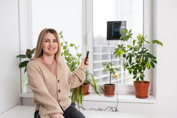 Woman cleaning windows at home with robotic cleaner.