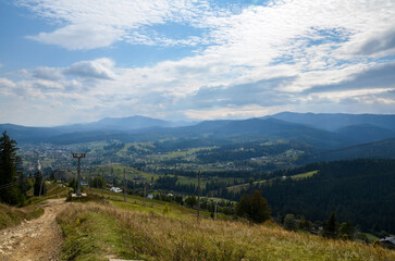 Fototapeta premium Green meadows with village, forest and surrounded Carpathian mountains in Ukraine. Scenic view of beautiful nature landscape