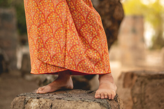 Japanese tradition and  beauty: details of the sexy bare feet of a japanese woman in traditional orange silk kimono at serene japanese garden