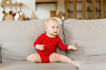 Portrait of small beautiful baby sitting on the sofa in living room at home