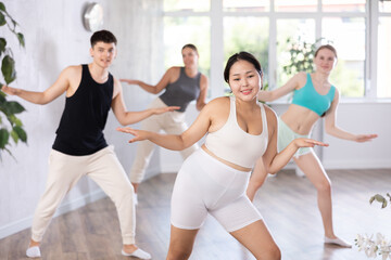 Full-bodied young woman training dance positions in light room during workout session