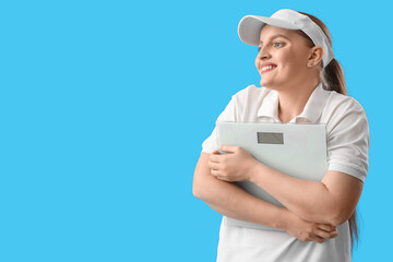 Happy young overweight woman with scales on blue background