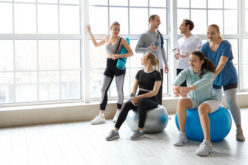 Obraz premium Group of sporty young people with bottles of water and equipment in gym