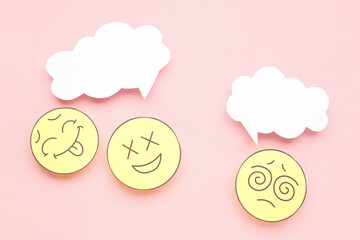 Paper faces with blank speech bubbles on pink background